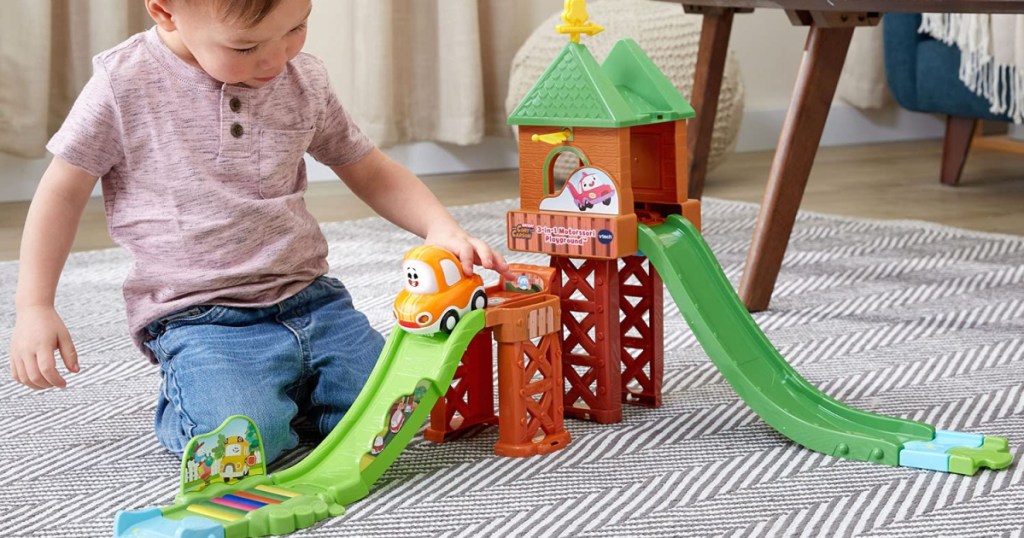 boy playing with playground playset on floor
