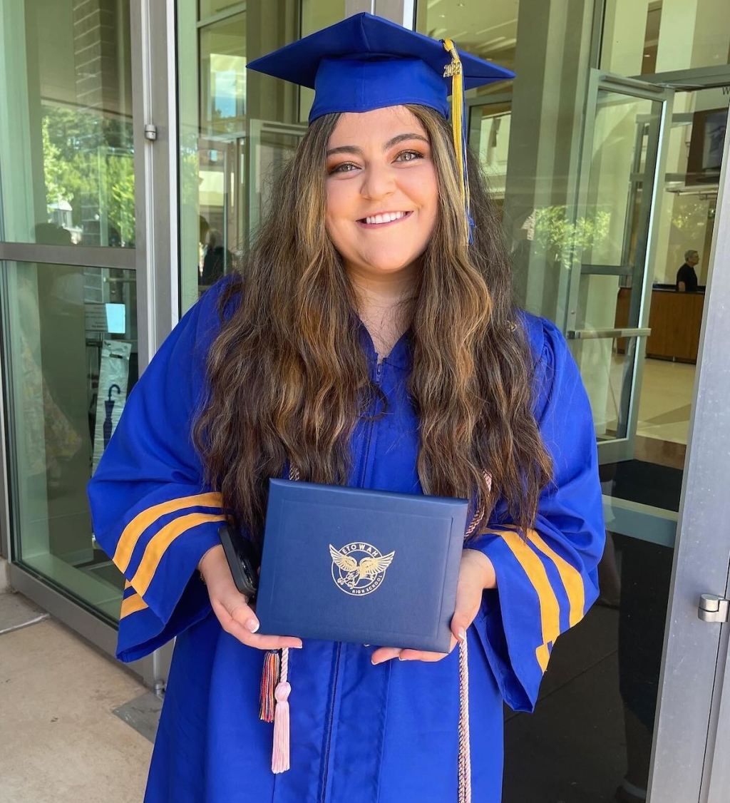 woman holding a high school graduation diploma wearing blue