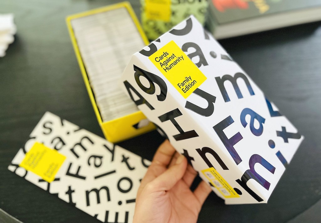 hand holding lid to cards against humanity family edition game box