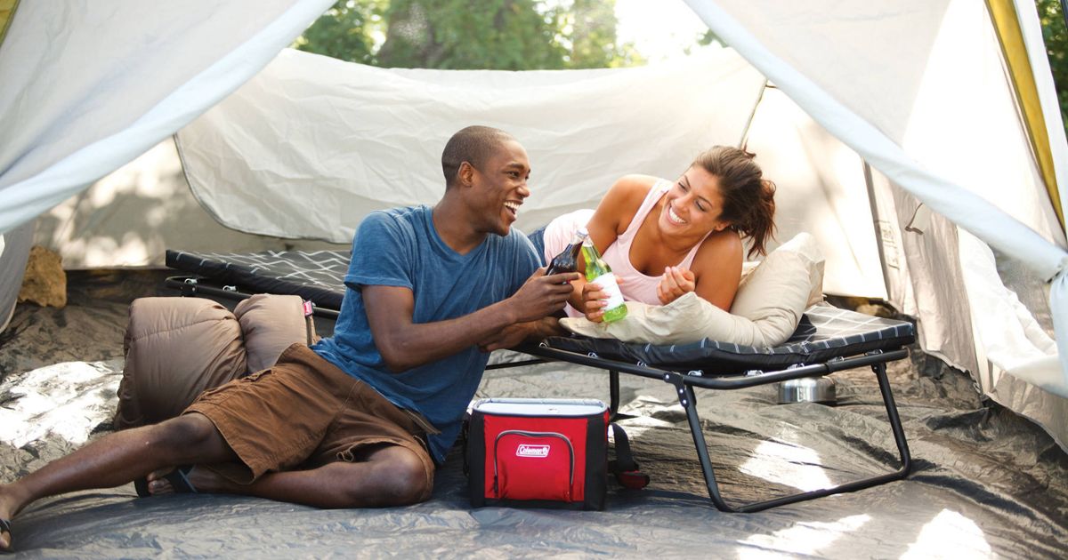 man sitting next to woman laying on cot