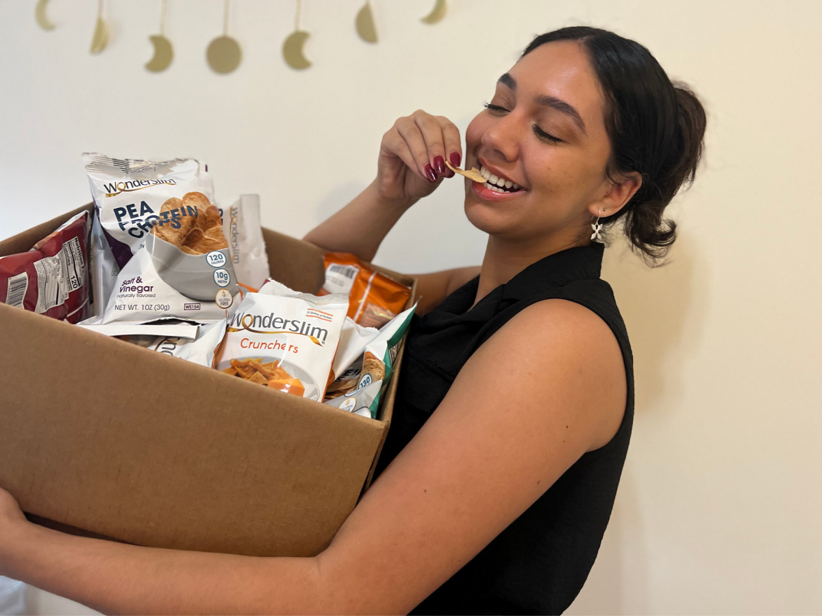 woman holding box and taking bite of a chip