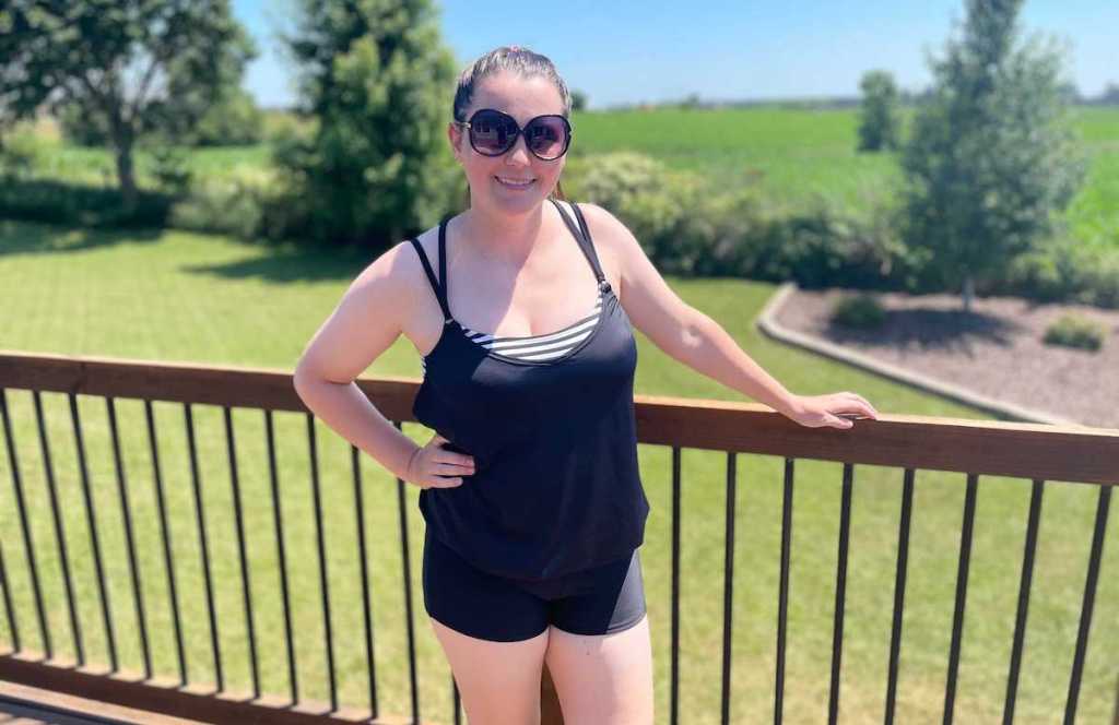 woman standing in front of deck railing wearing modest swimwear