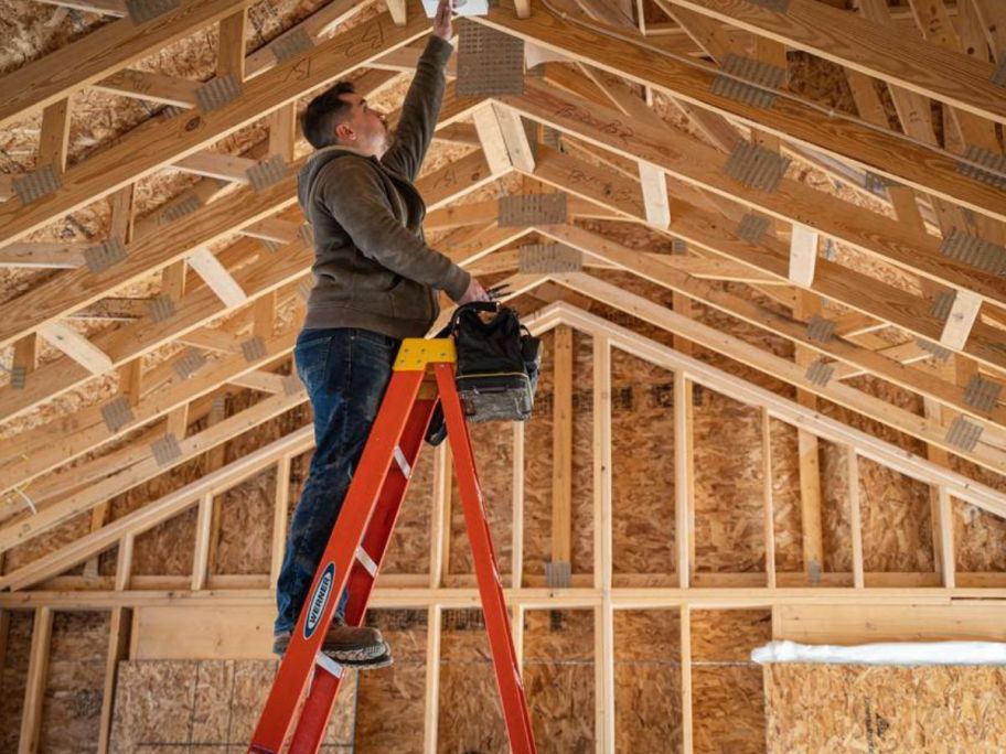 man on ladder doing construction in unfinished house