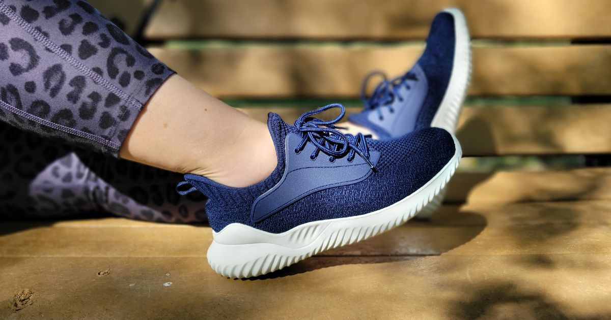 woman wearing blue walking shoes resting feet on bench