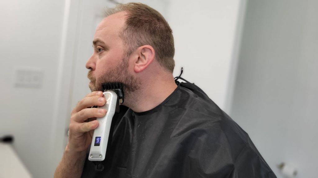man using hair clippers on his face