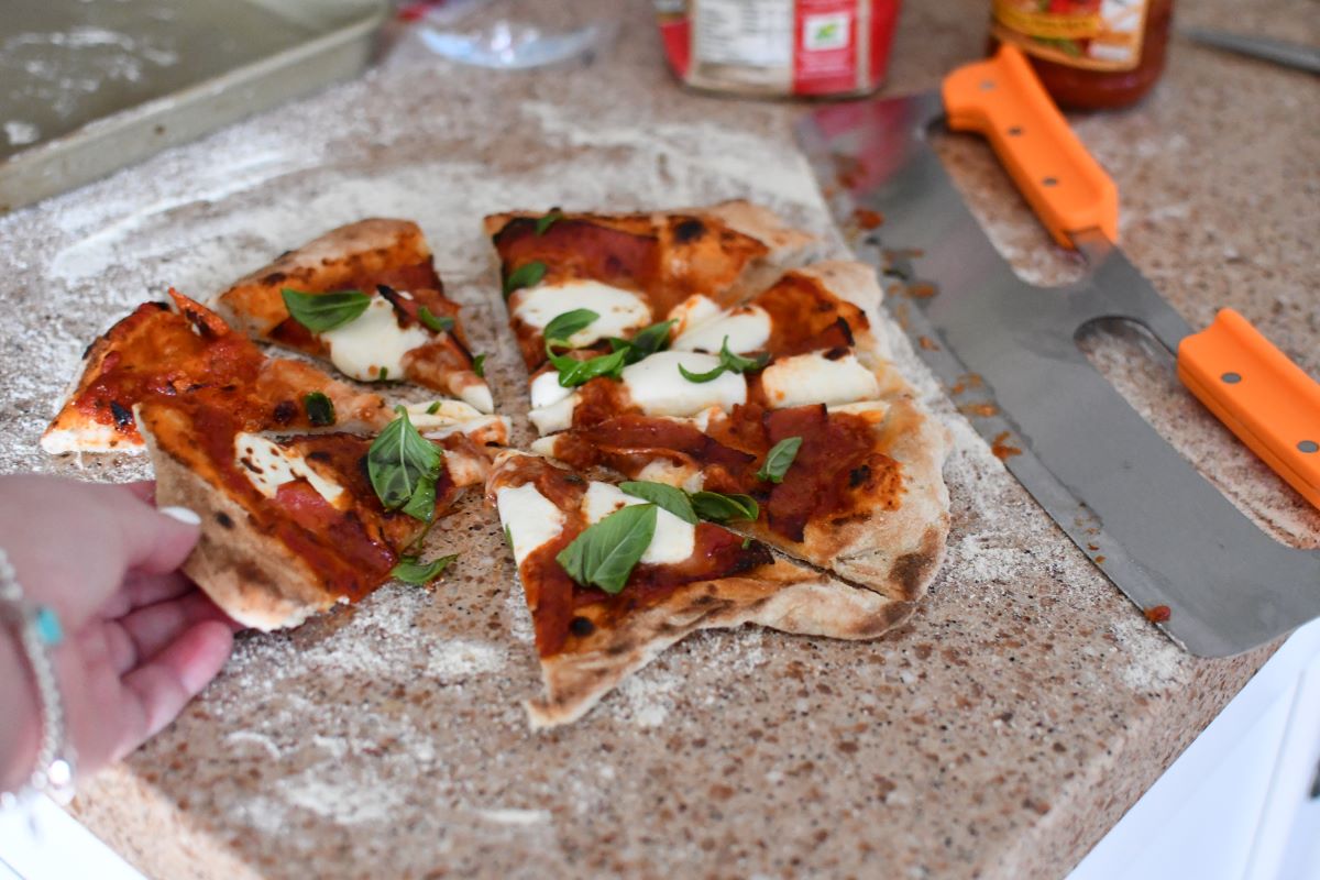 hand grabbing a piece of pizza