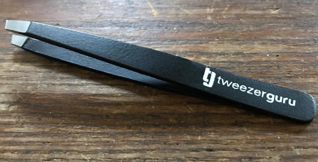 Black tweezers on a wood table