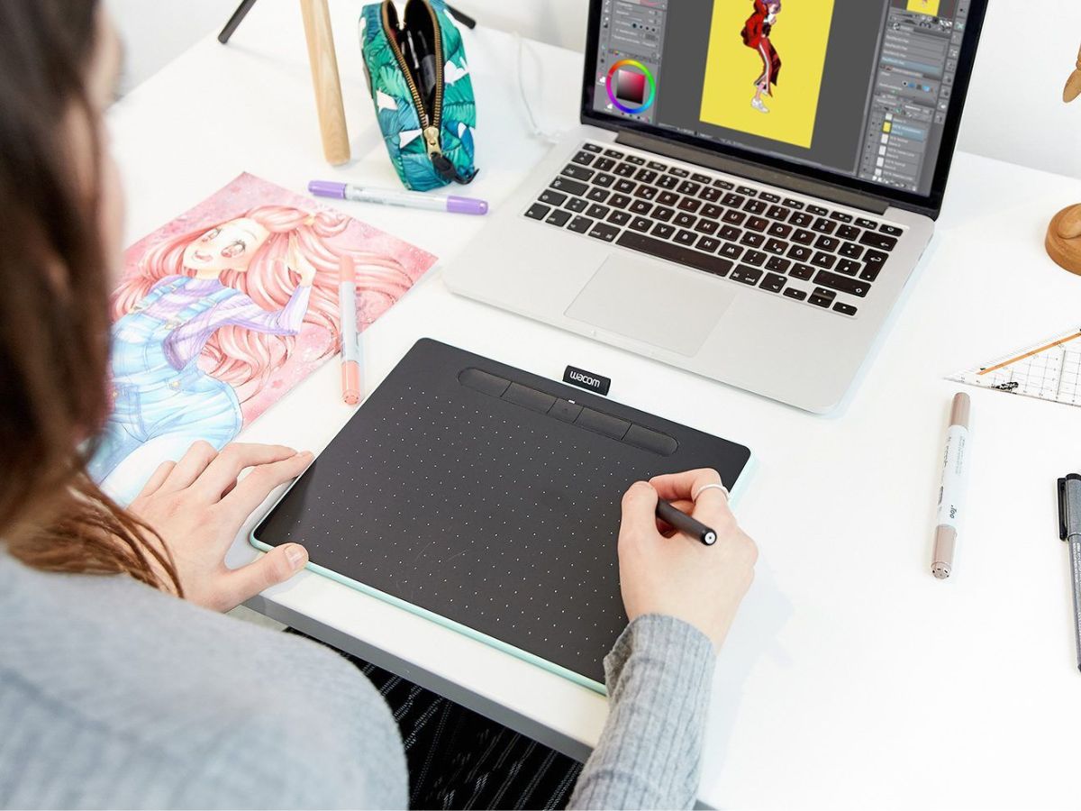 woman using a Wacom drawing tablet to create art on a laptop