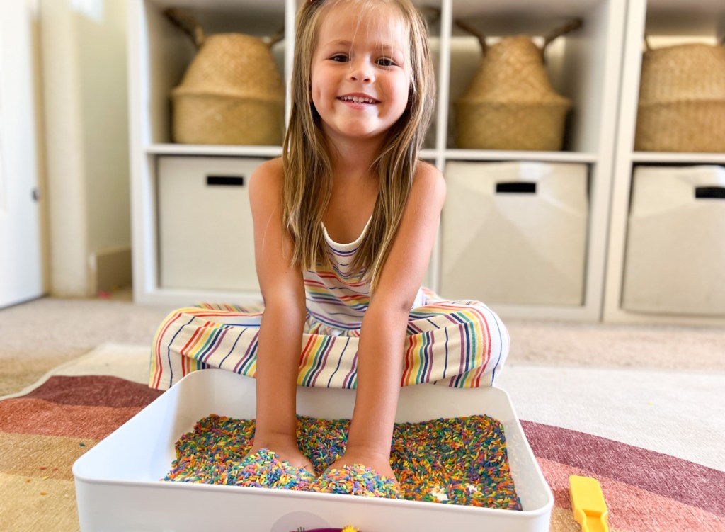 girl with hands in rainbow rice