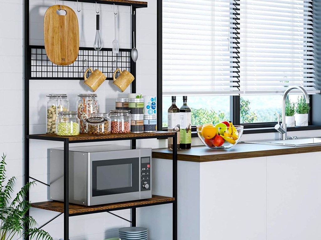 metal and wood shelf with microwave, storage containers and cutting board and other kitchen utensils