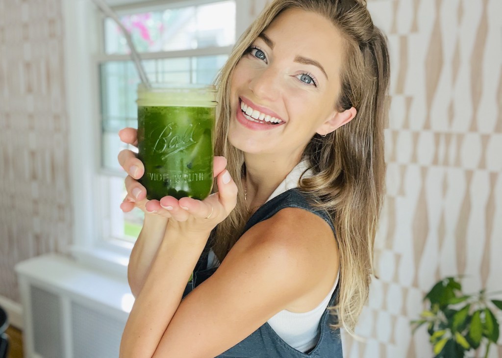 woman holding up glass ball cup with green matcha inside