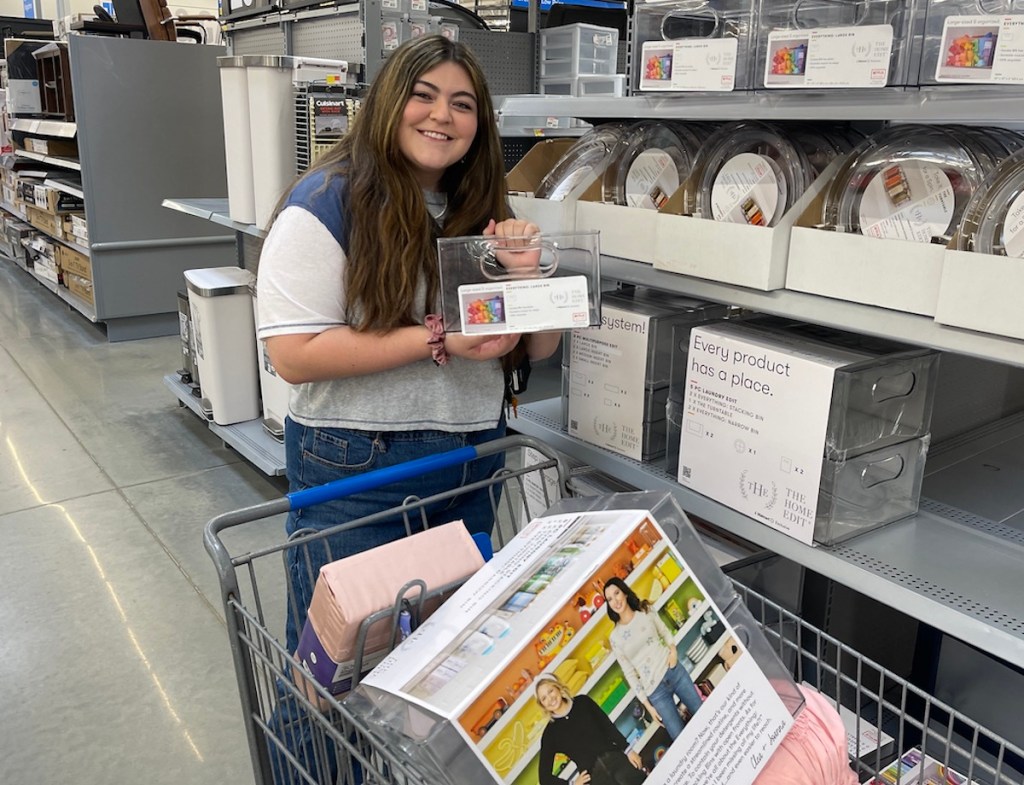 girl standing in walmart aisle holding clear organizers for dorm room essentials