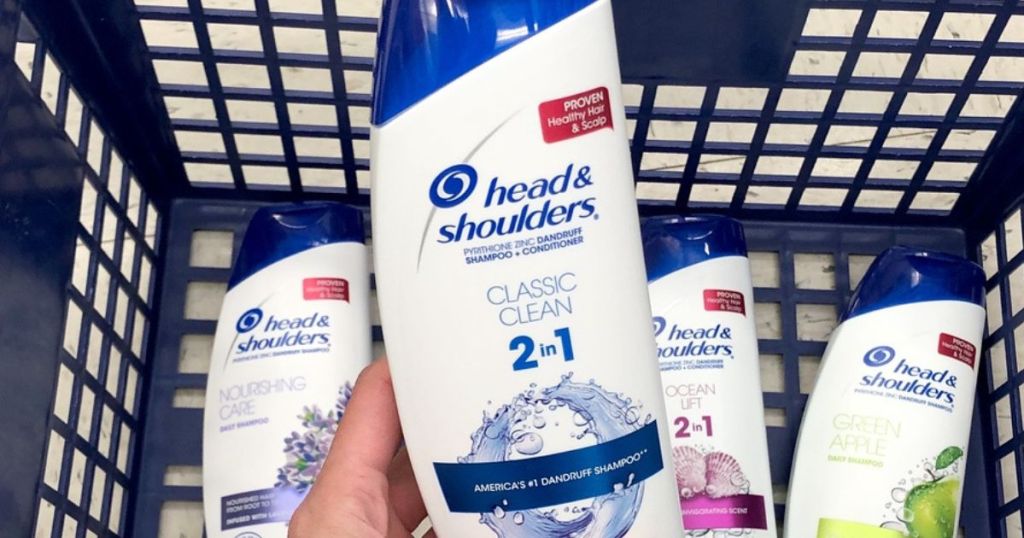 Head & Shoulders 2-in-1 being held in a hand over a basket filled with other types of head and shoulders