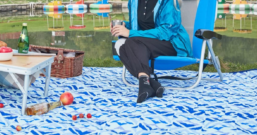 woman sitting in camping chairs on outdoor blanket in park