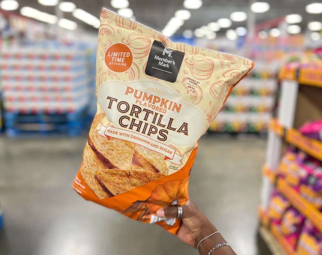 woman holding a bag of Member's Mark Pumpkin Tortilla Chips