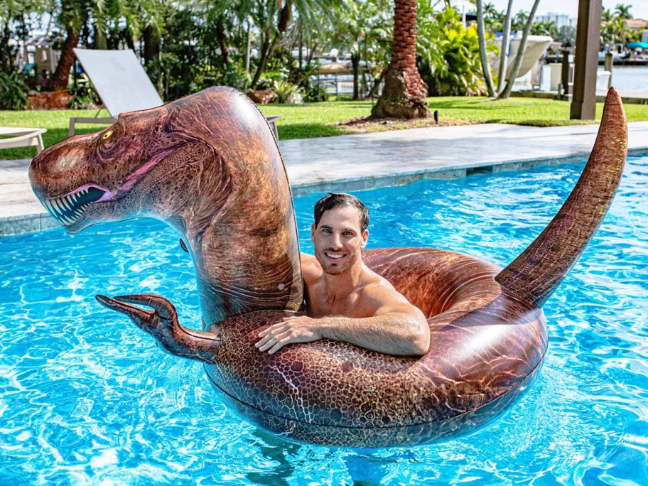 man floating in a brown dinosaur pool float