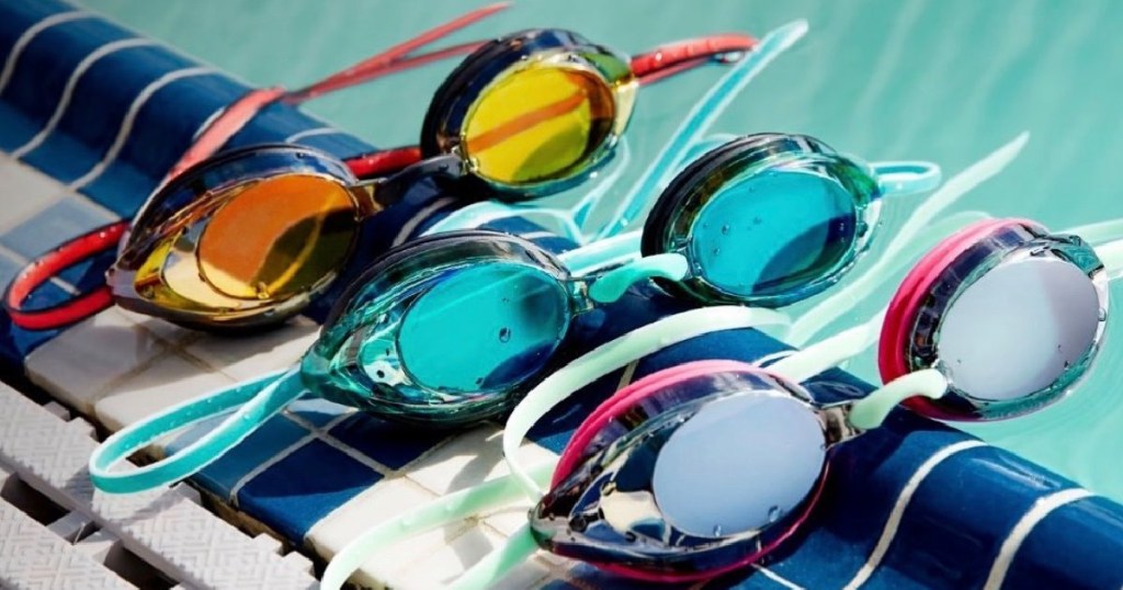 three pairs of swim googles on edge of pool