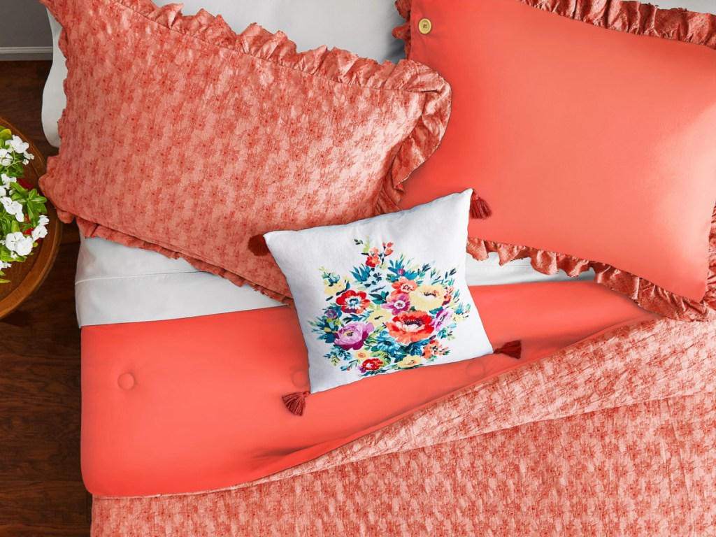 coral comforter on bed with floral accent pillow