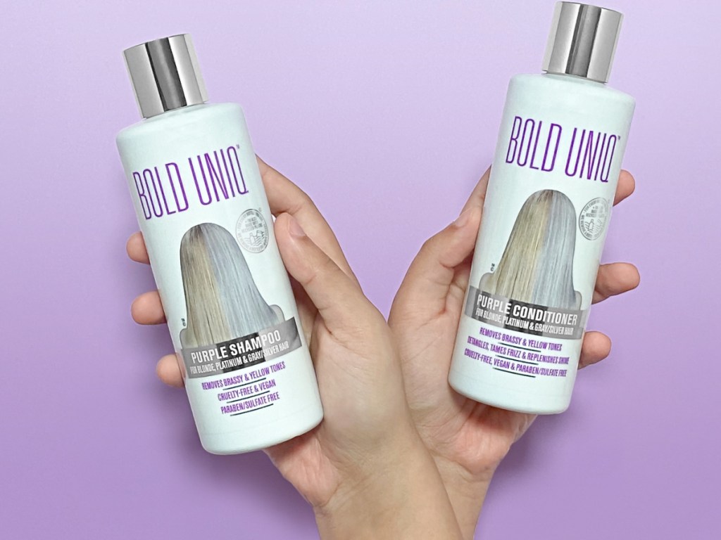 hands holding shampoo and conditioner