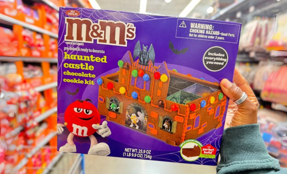 a womans hand holding a M&Ms halloween house cookie building kit