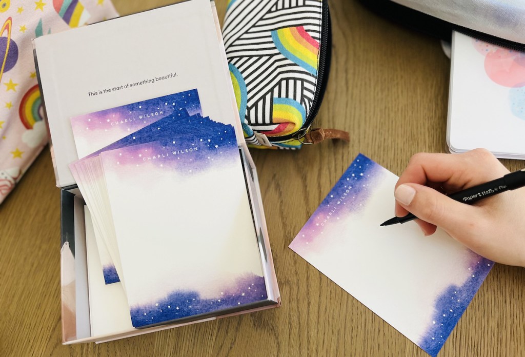 hand holding pen over kids stationery on table