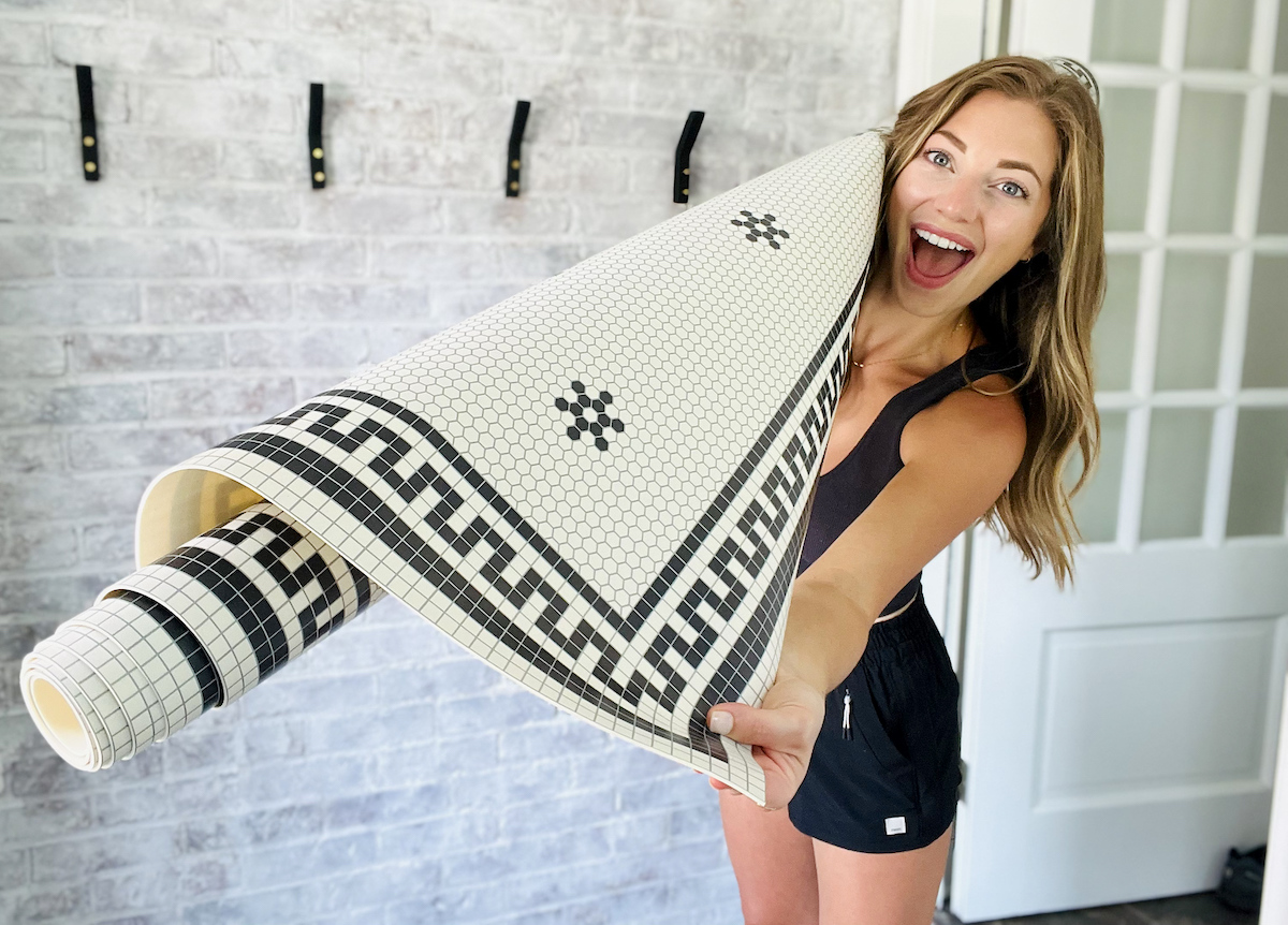 woman holding rolled up vinyl floor mat with black and white tile design