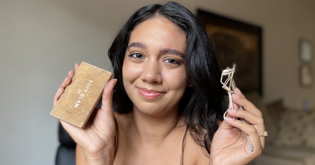 woman holding makeup and eyelash curler