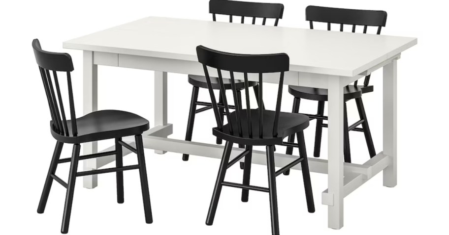 a white dining table set with 3 black chairs