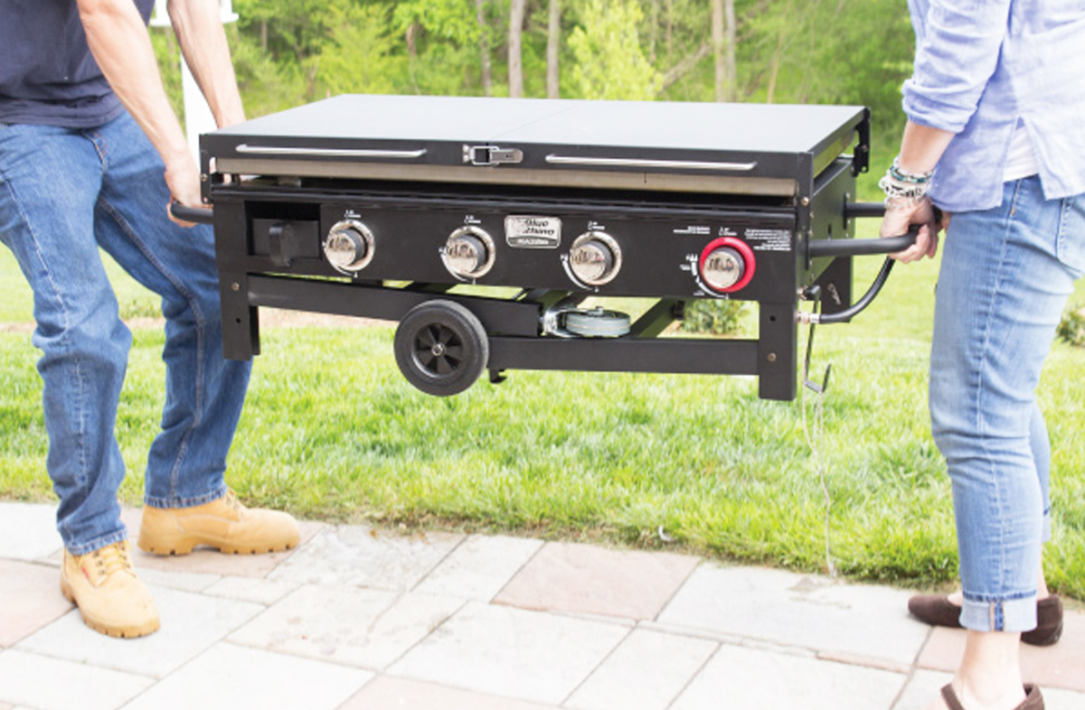 two people carrying flat top grill