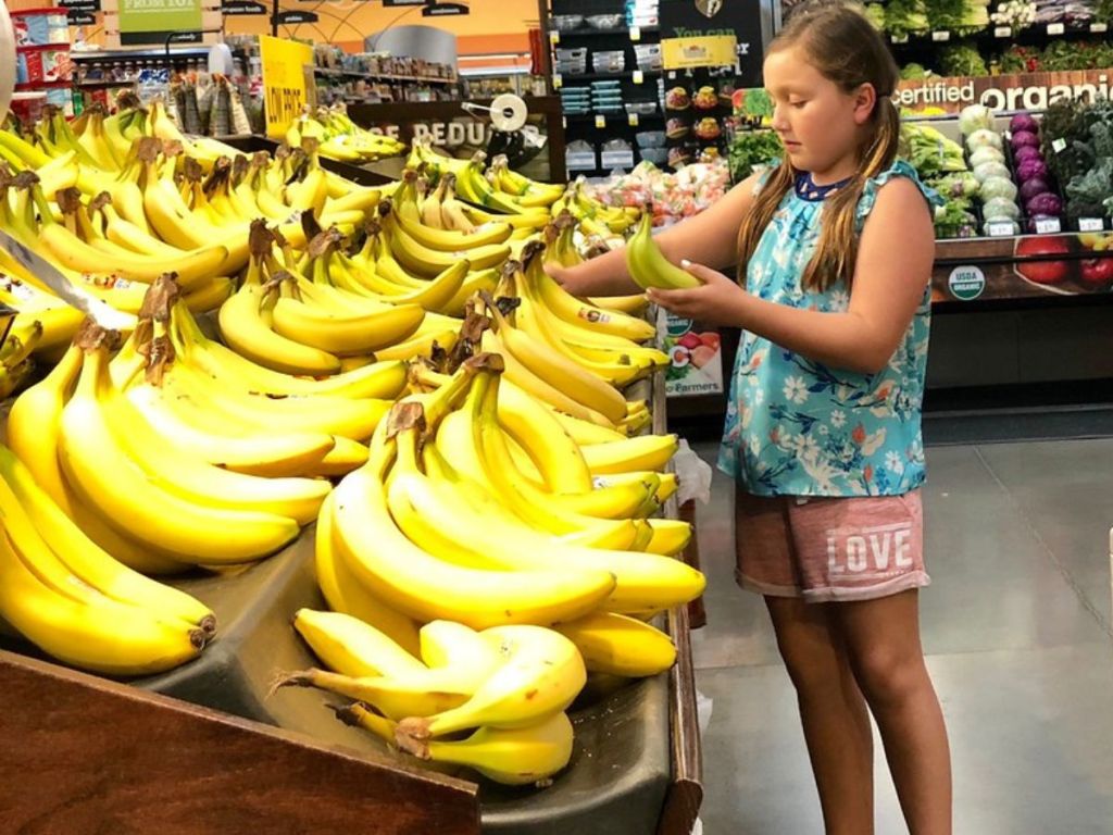 Little girl in produce section of grocery store