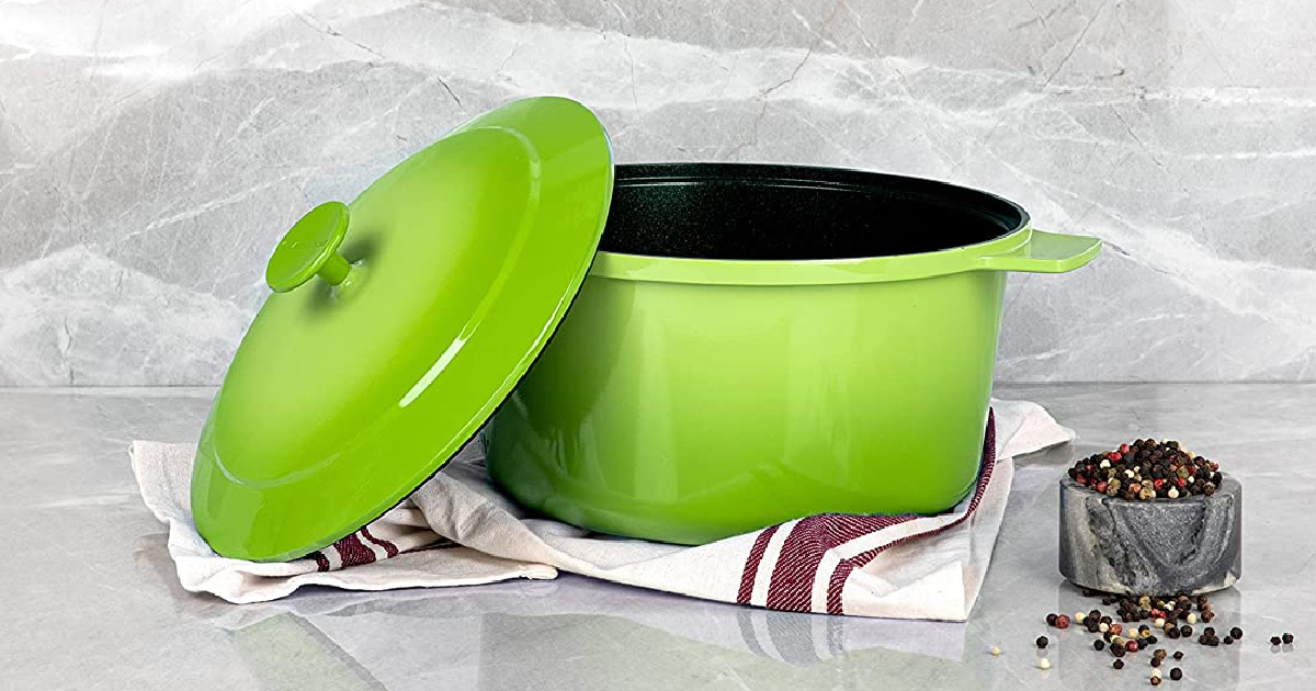 Granitestone diamond Dutch Oven in green sitting on a kitchen towel next to peppercorns with a marble background