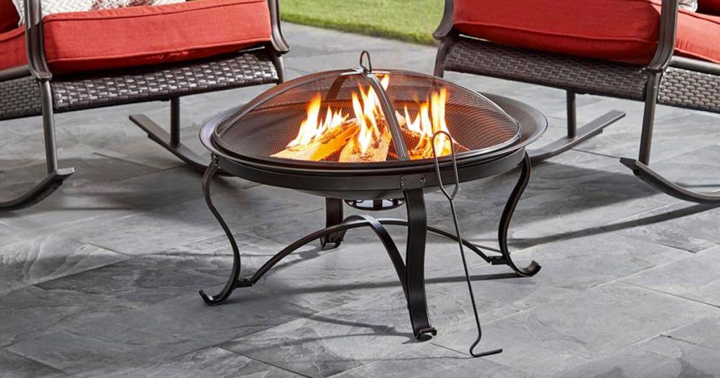 round fire pit on patio with wood poker leaning against it