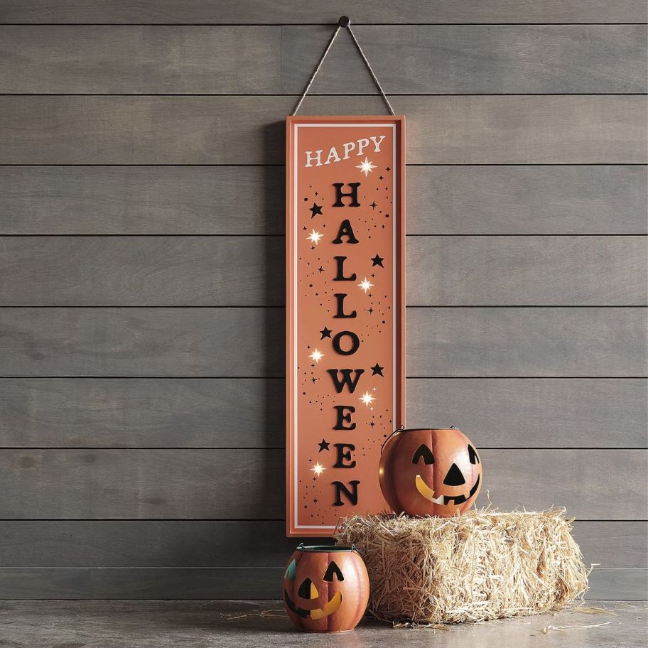 two metal jack o lanterns next to a bail of hay 