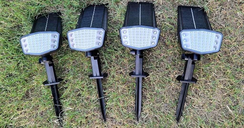 4 solar lights laying side by side on grass