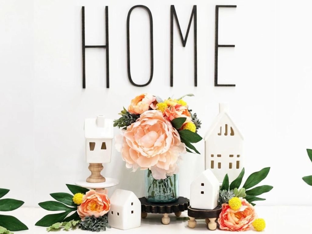 wooden HOME letters hung on wall and flowers on table beneath