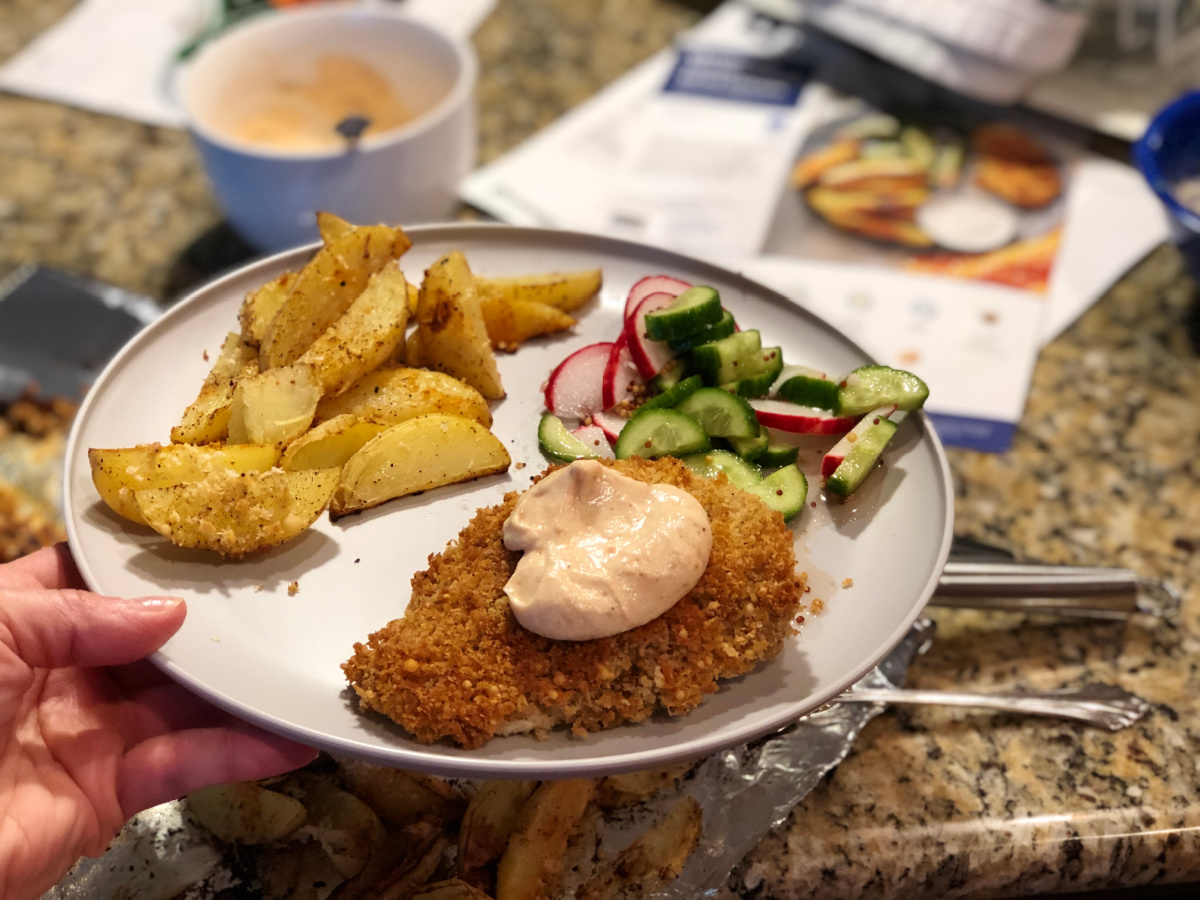 Woman displaying Blue Apron Meals and her baked chicken recipe cards