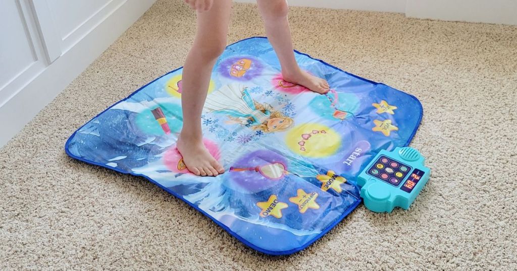 Little girls legs and feet shown stepping on a kids dance mat toy