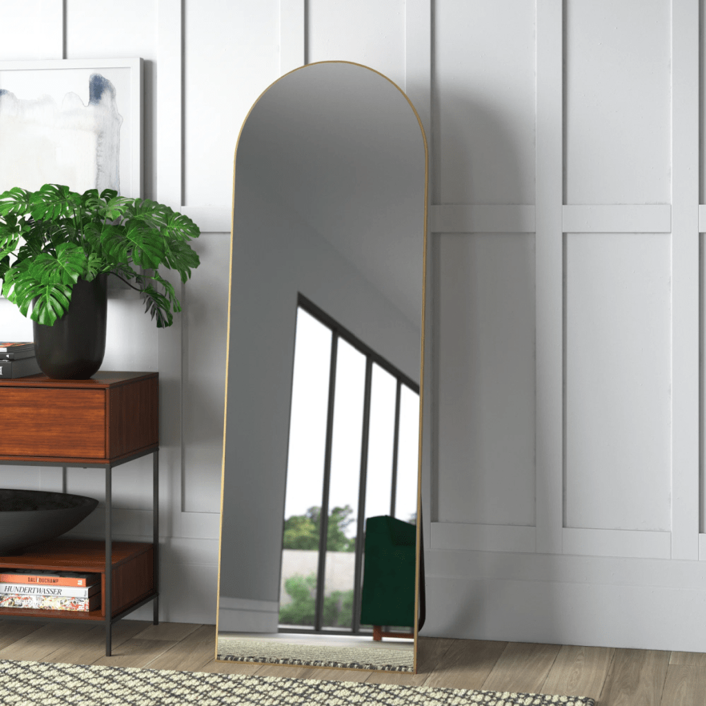 A full length Greta Arch Wood Mirror displayed in a home