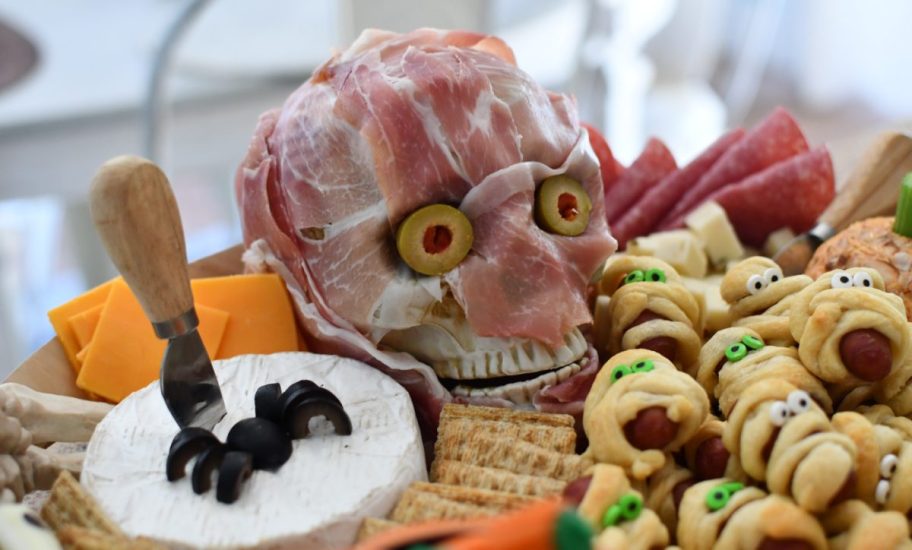 A halloween charcuterie board with a meat-covered skull