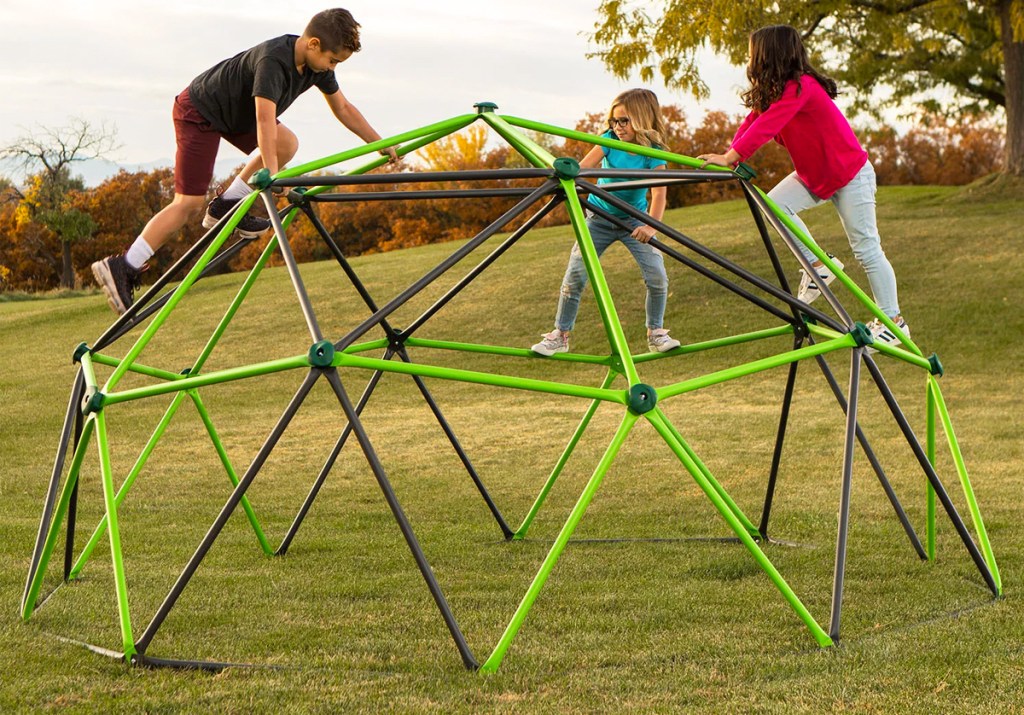 three kids playing on green climbing dome