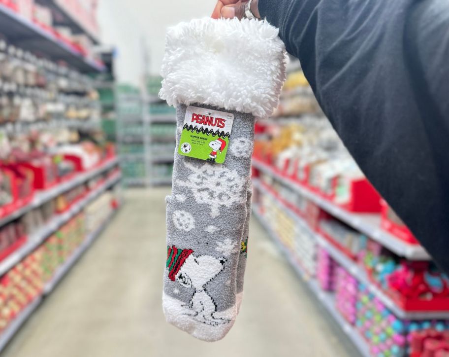 a womans hand holding a pair of peanuts slipper socks