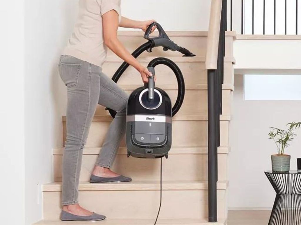 Woman using a small vacuum on some stairs