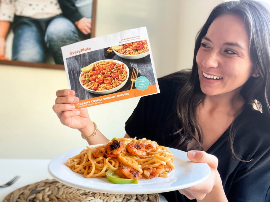 woman holding a plate of pasta and an Everyplate recipe card