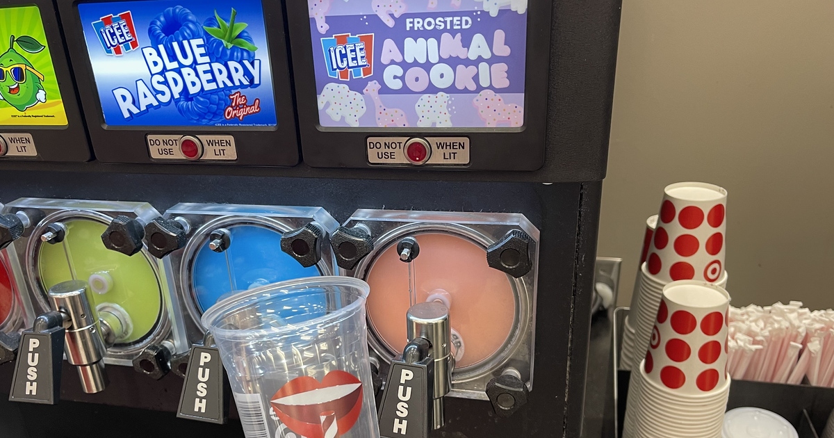 holdin an empty cup in front of an Icee machine