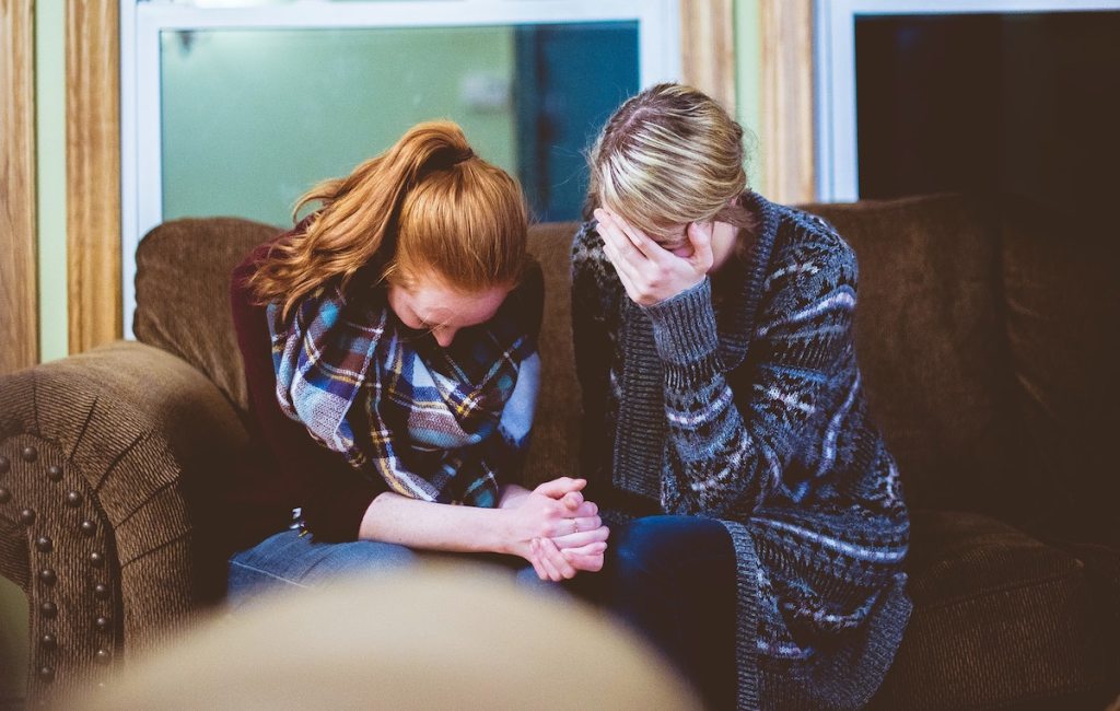 two woman sitting on couch crying