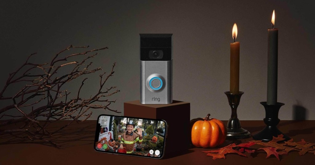 Ring doorbell displayed with candles, a phone, and a pumpkin