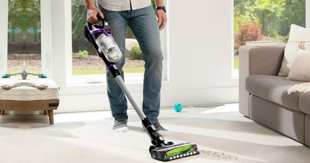 Man using a Bissel Powerglide Pet Eraser Vacuum on carpet