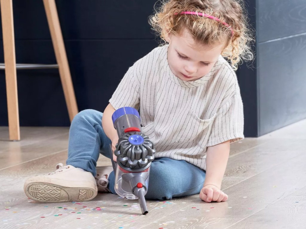 little girl using Dyson Cordless Toy Vacuum with short handle