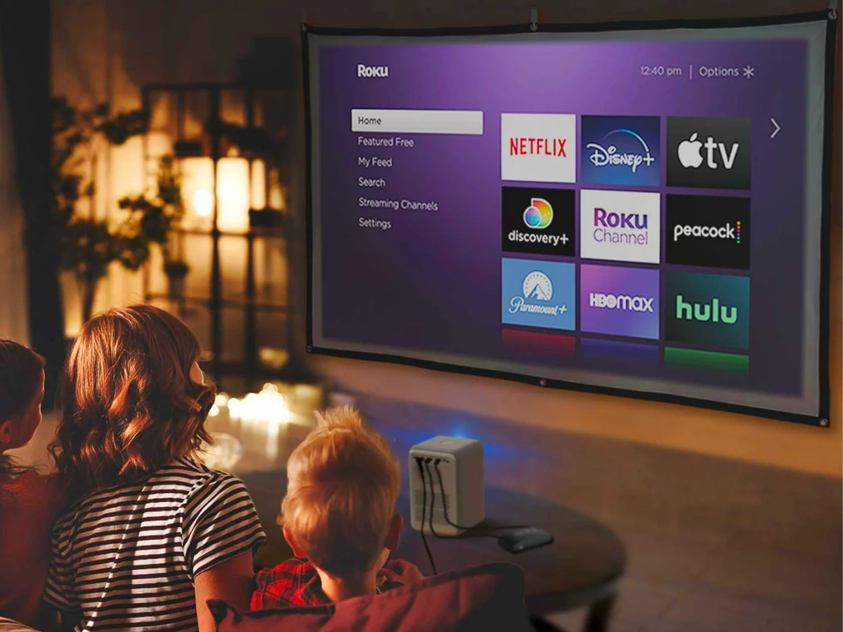 family watching a roku home screen on a projector and mobile screen