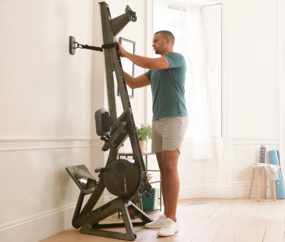 man leaning workout machine against wall